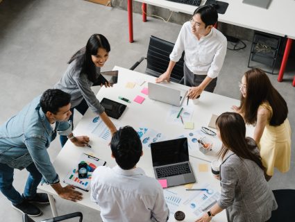 Multiracial group of young creative people in smart casual wear discussing business brainstorming meeting ideas mobile application software design project in modern office. Coworker teamwork concept.